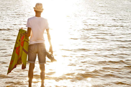 young man on the beach watching the sea at sunset summerの写真素材
