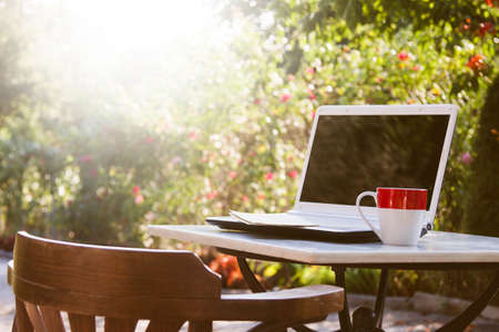laptop and coffee cup on outdoor tableの写真素材