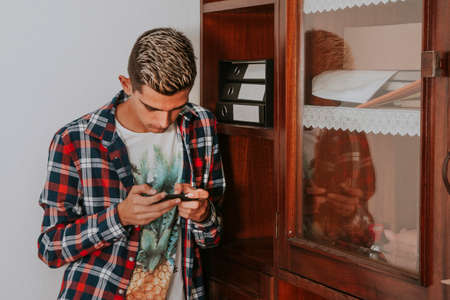 young man with mobile phone at homeの写真素材