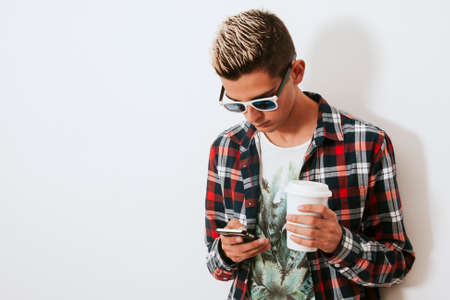 isolated young man with mobile phone and cup of coffeeの写真素材