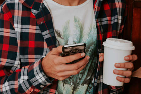 smart phone in hand in the foreground with cupの写真素材