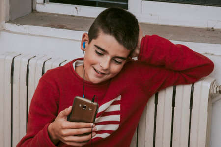 young boy listening to music with mobile phoneの写真素材