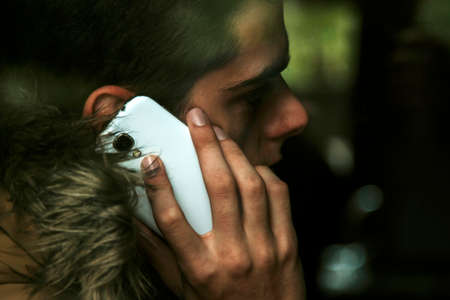 young man talking on mobile phone behind glassの写真素材