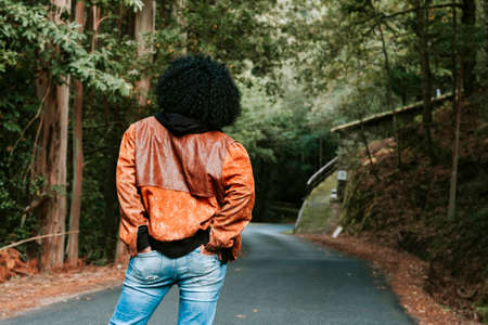 woman back on the mountain road with hands in pocketsの写真素材