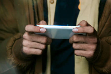 hands with mobile phone behind the glass of the windowの写真素材