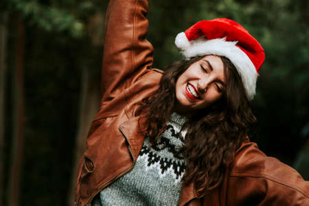 attractive young woman smiling with christmas hat outdoorsの写真素材