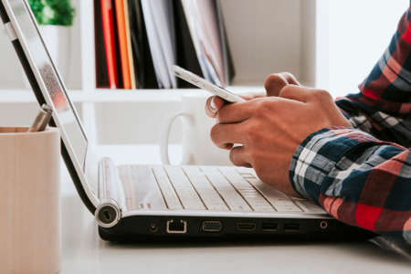 young man at office with mobile phone and laptop