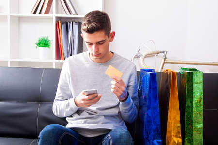 young man buying with mobile phone from homeの写真素材