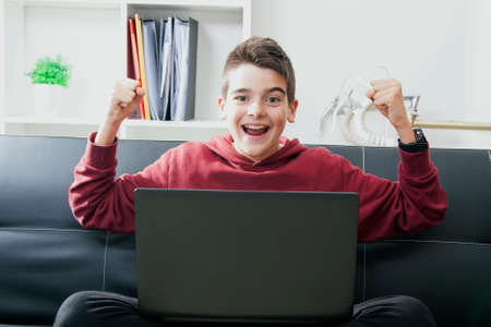 child with laptop celebrating success with enthusiasmの写真素材