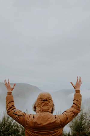 young with the arms on high looking at the landscape with fog