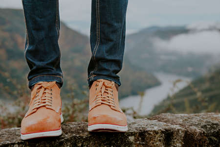 feet with hiking boots with the mountains in the background, concept of adventure and travelersの写真素材