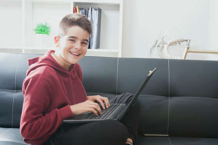 child with computer laptop sitting in the sofa of houseの写真素材