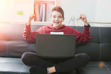 child with computer laptop celebrating the success in the living room of House