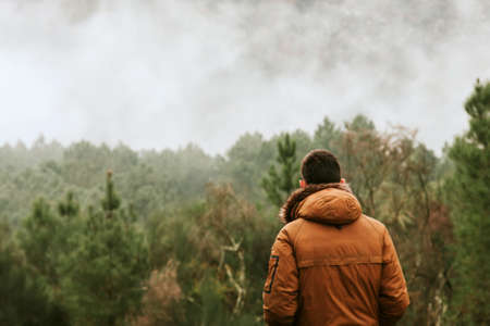 young man in the forest looking at the landscape