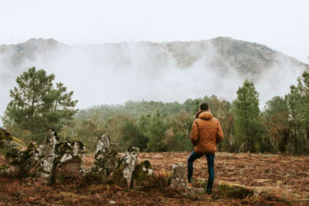 young man in the forest looking at the landscape