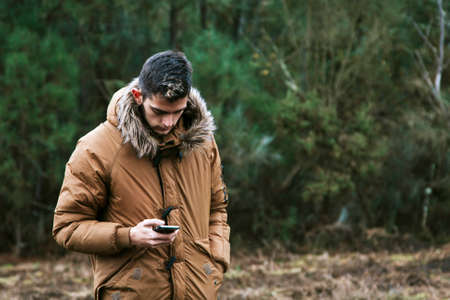young man with the cellphone in the forestの写真素材