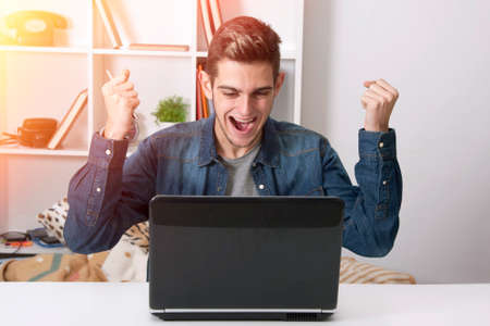 young man celebrating success with the laptopの写真素材