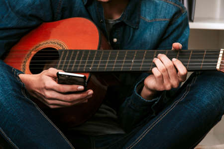 hands with the mobile phone and the guitarの写真素材