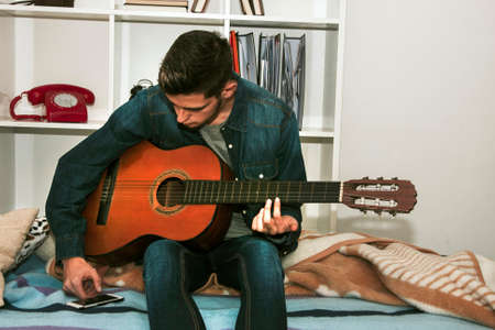 young man with the guitar and the phone in the room