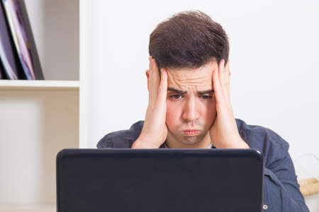 young man in front of the computer laptop concentrated or overwhelmed