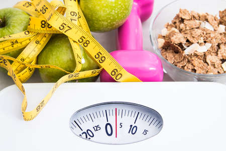 scale with cereals, fruit, weight and tape measure and concept of diet and healthy lifestyleの写真素材