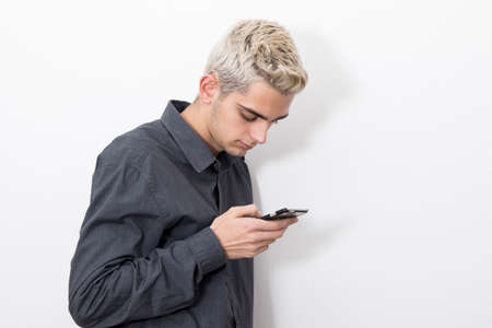 man young teen to her fashion with the phone mobile on wall whiteの写真素材