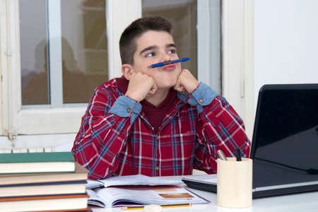 child distracted thinking on the desk of the school or homeの写真素材