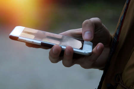 close-up of hands with the phone at sunsetの写真素材