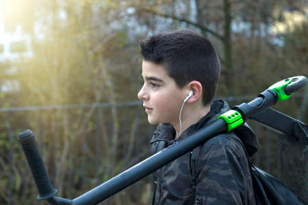 child with the scooter while listening to music in the streetの写真素材