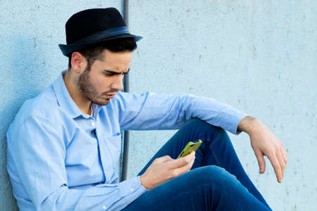 young man typing on the phone on the street