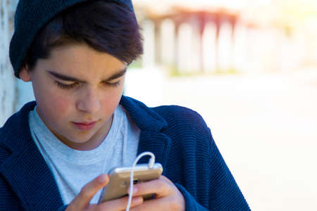 child with a mobile phone in the street about the blue wall