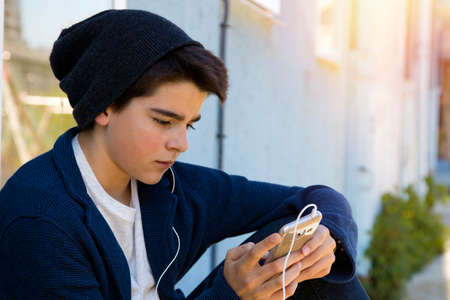 child with a mobile phone in the street about the blue wall