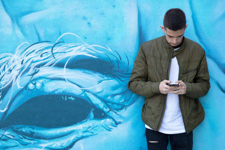 young man with mobile phone on streetの写真素材