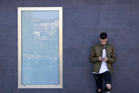 young man with mobile phone on streetの写真素材