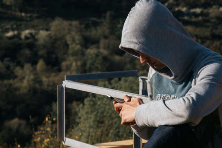 teenager with mobile phone outdoors coat with hoodの写真素材