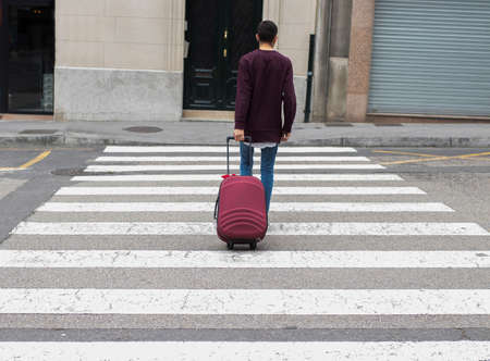 young man across the street with the suitcaseの写真素材