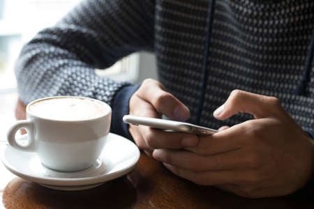 having breakfast with the cellphone in the cafeteriaの写真素材