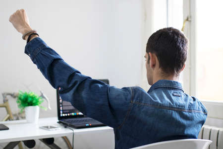 young man with the laptop in the room celebrating euphoricの写真素材
