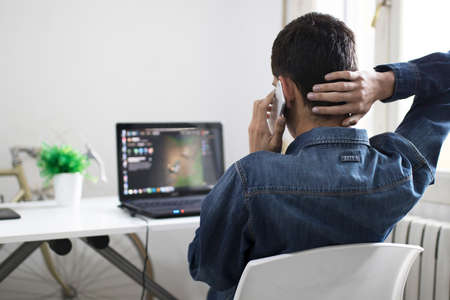 young man with the mobile phone and the laptopの写真素材