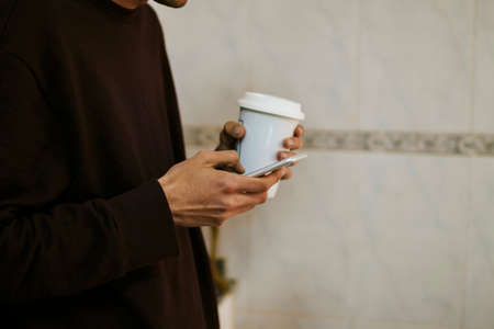 closeup of the hand with the mobile phone and coffee cup