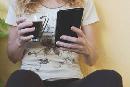 closeup of hands with a cup of coffee and mobile phone