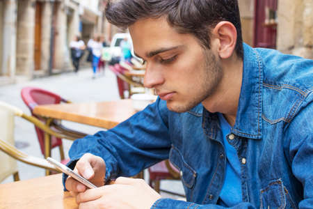 young boy with the cellphone on the terrace of the cafeの写真素材