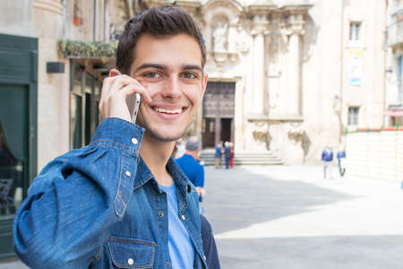 teen young man with the phone in the street of the city