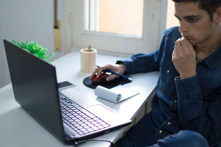 young man studying and working with the computer taking notesの写真素材