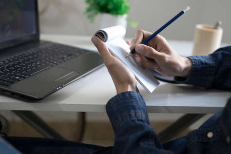 young man studying and working with the computer taking notesの写真素材