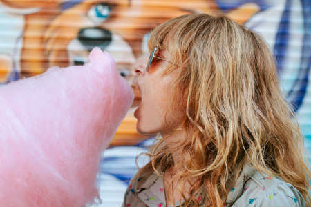 girl eating cotton candy at the amusement parkの写真素材