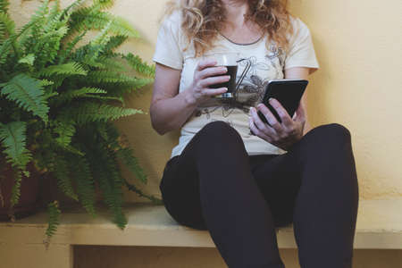 closeup of hands with a cup of coffee and mobile phoneの写真素材
