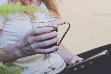 closeup of hands with a cup of coffee and mobile phoneの写真素材