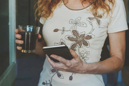 closeup of hands with a cup of coffee and mobile phoneの写真素材