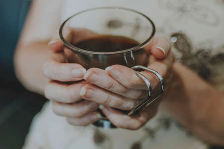 hands of woman with black coffee mugの写真素材